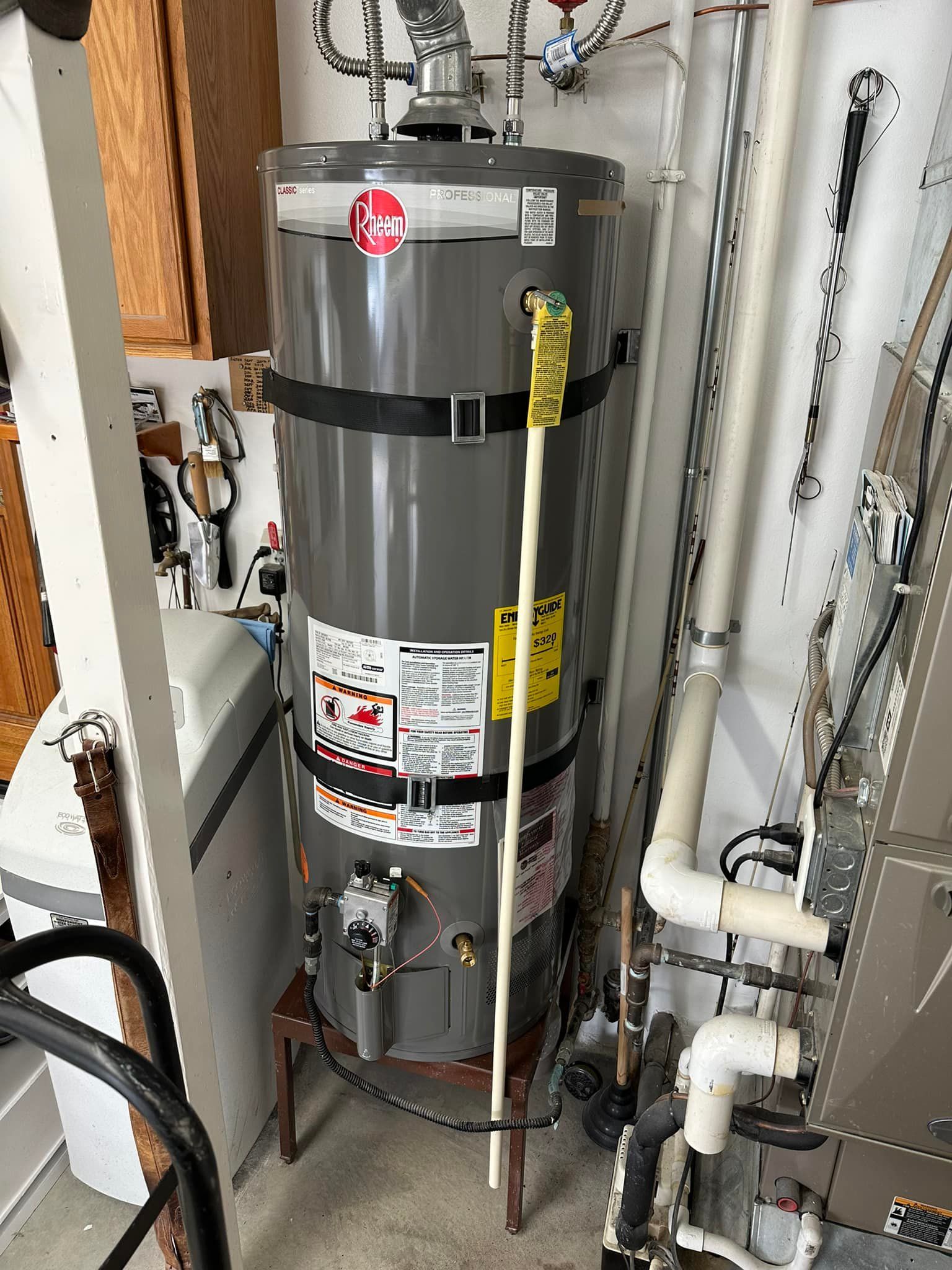 A gray water heater is sitting on top of a wooden stool in a room.