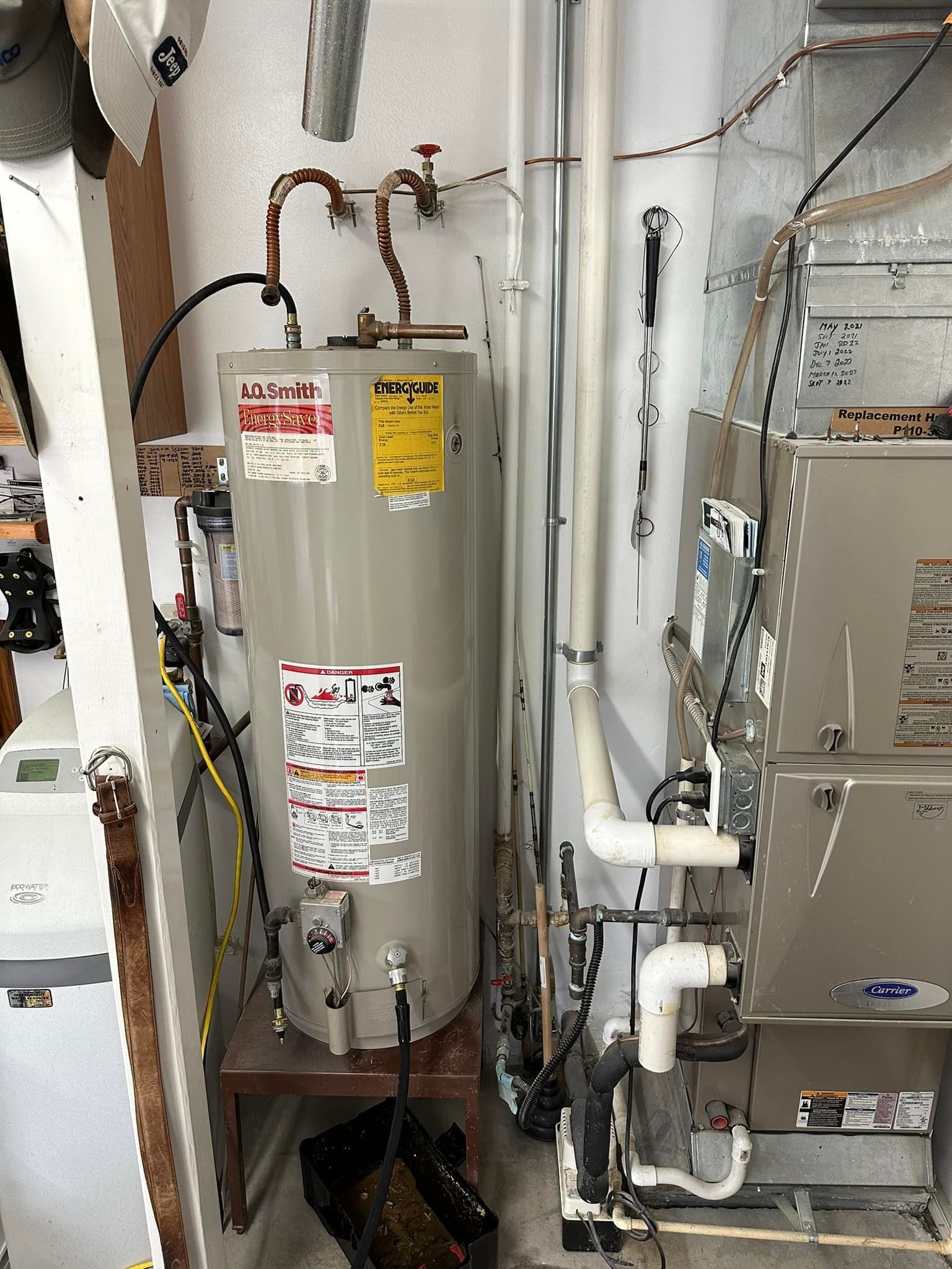 A water heater is sitting in a room next to a furnace.