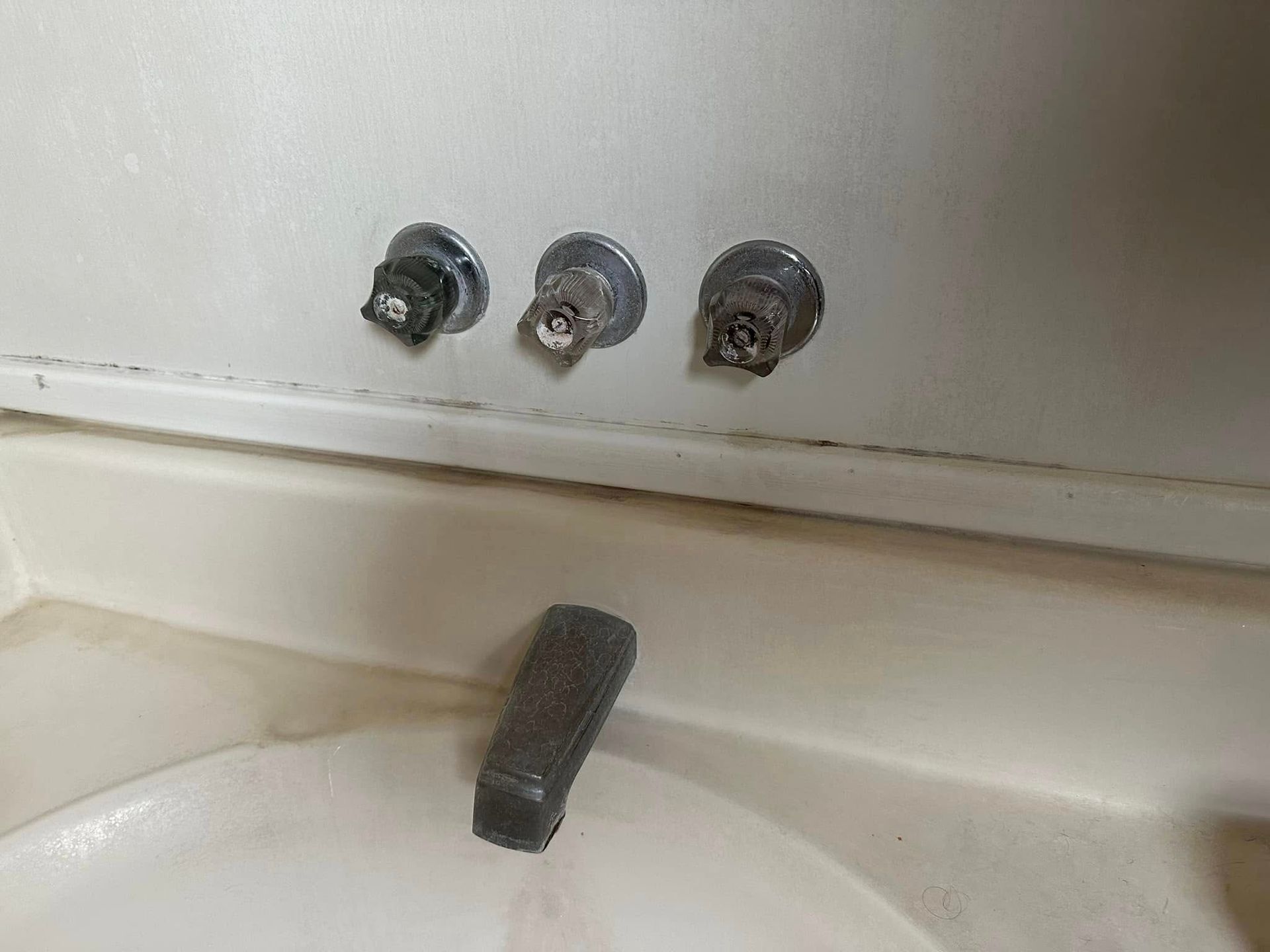 A close up of a bathroom sink with three faucets.