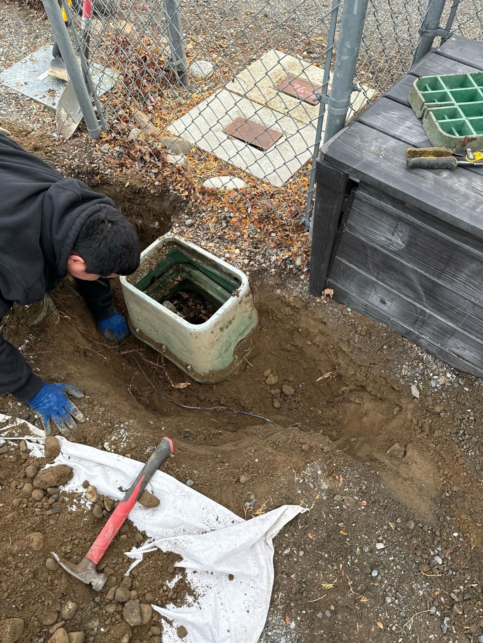 A man is digging a hole in the ground with a shovel.