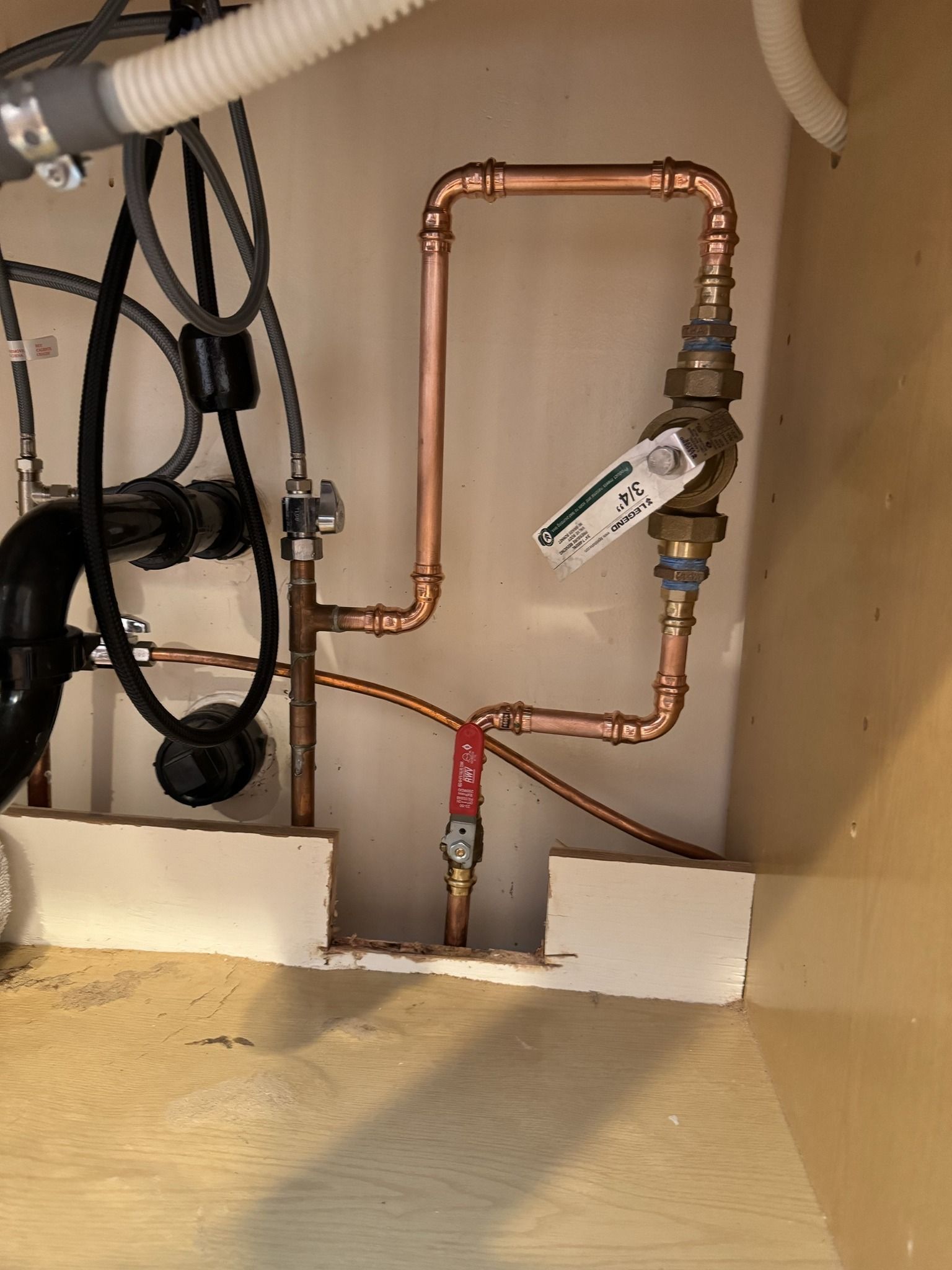 A close up of a copper pipe under a sink in a kitchen.