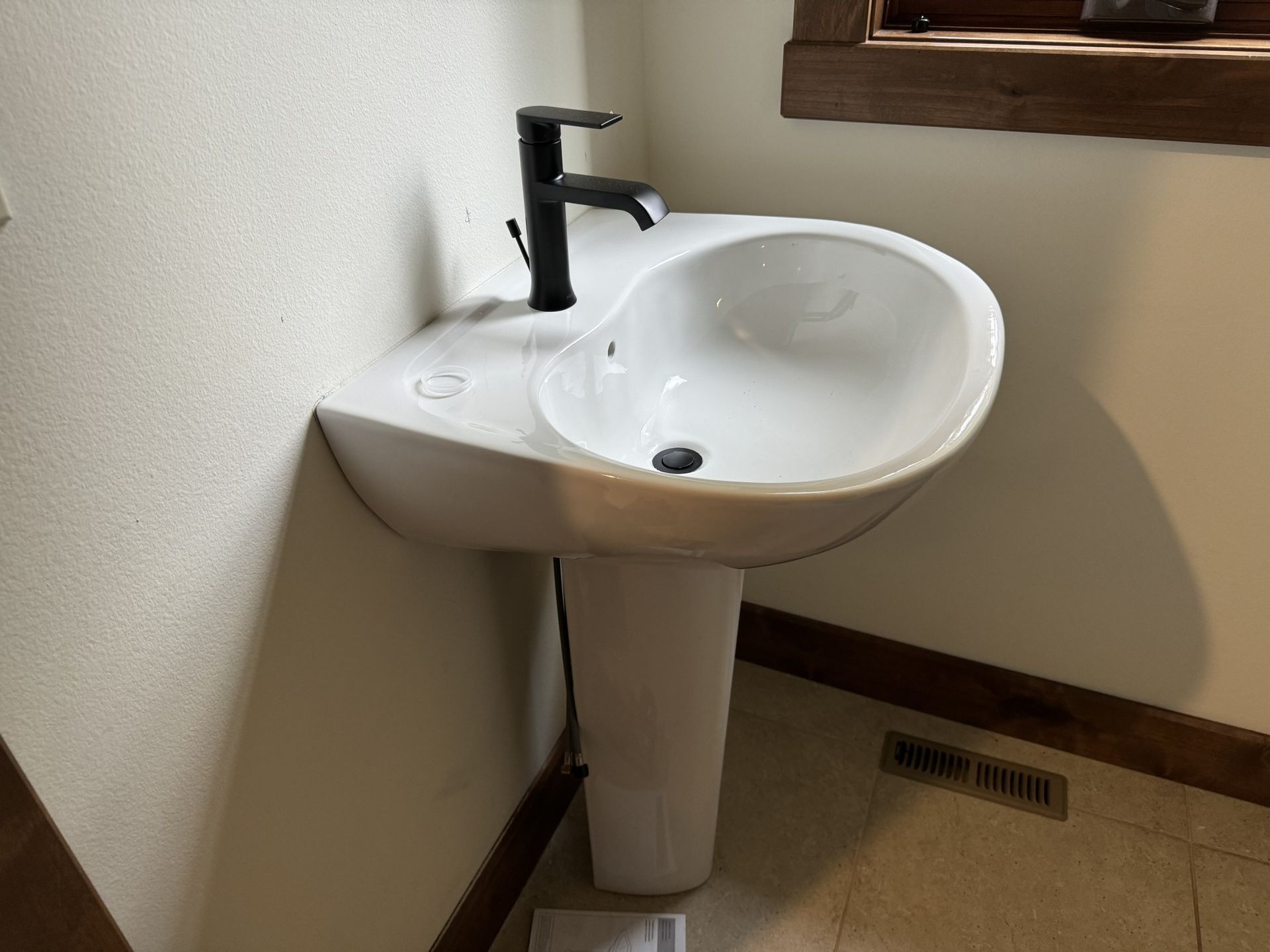 A white pedestal sink with a black faucet in a bathroom.