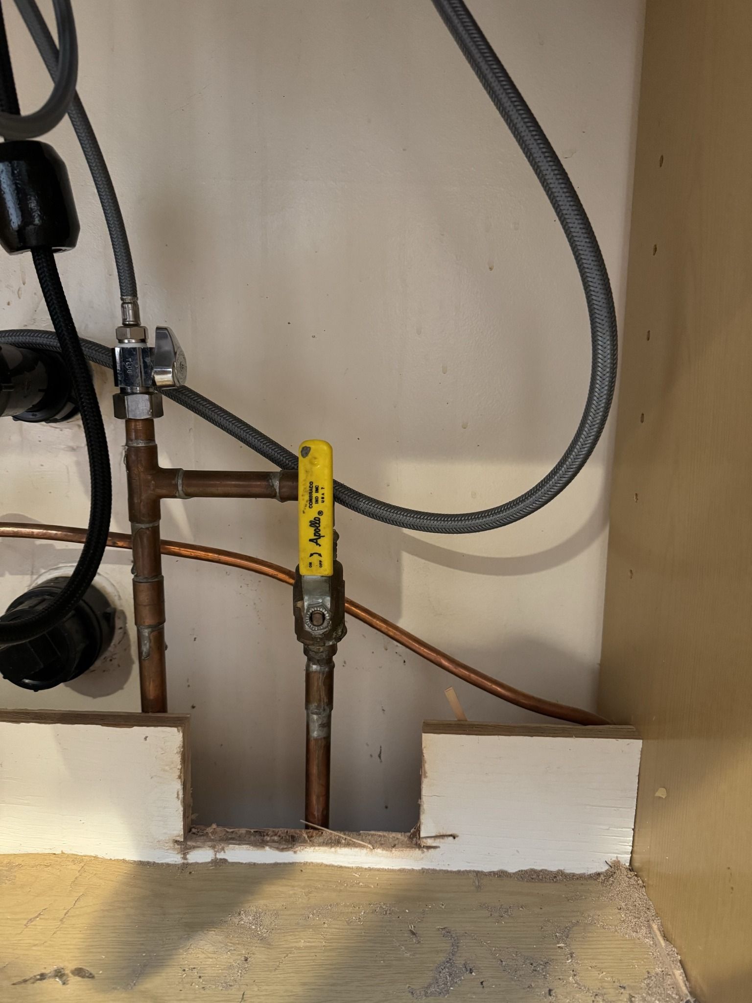 A yellow gas valve is attached to a copper pipe