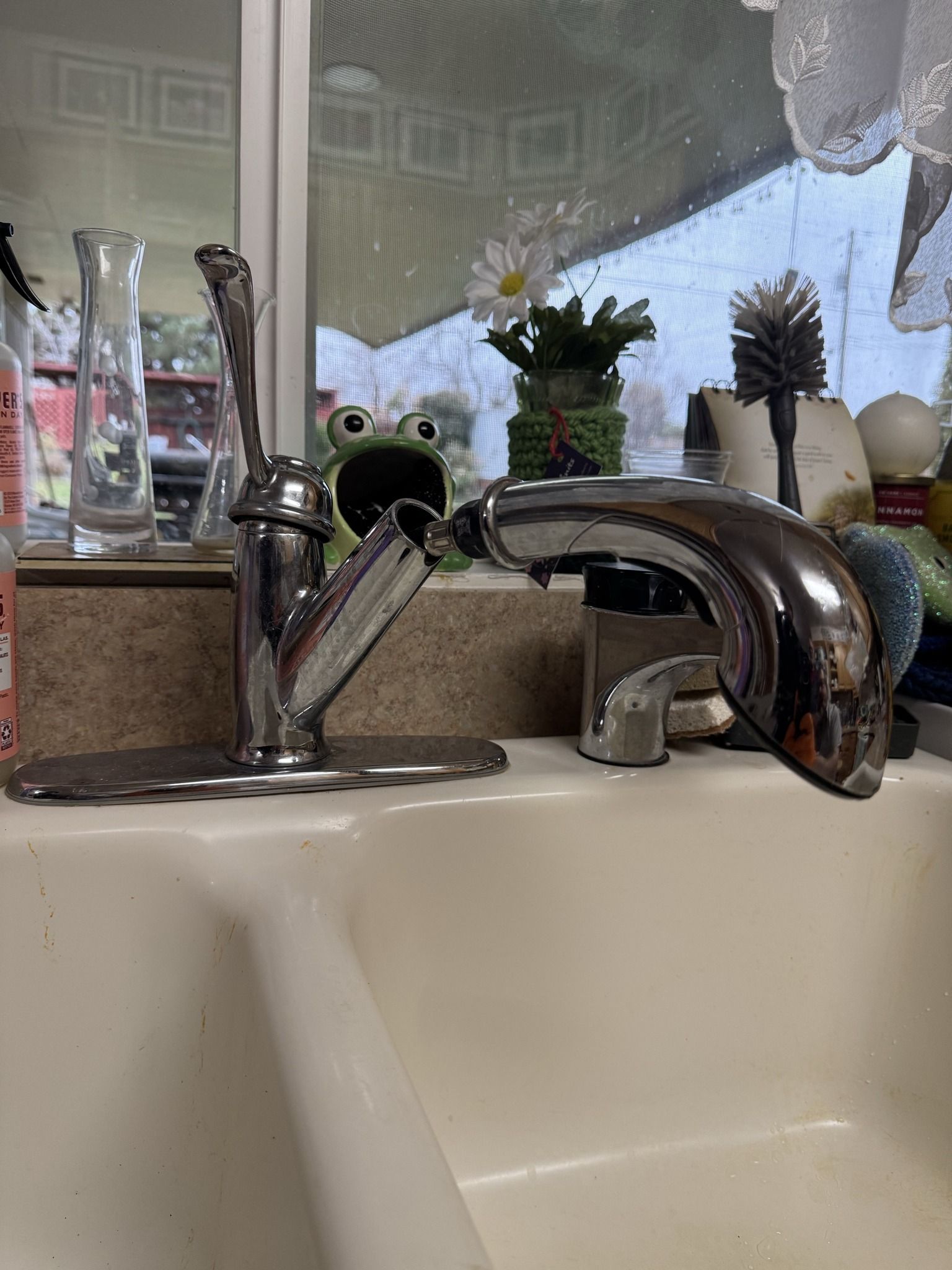 A close up of a sink with a frog on the counter.