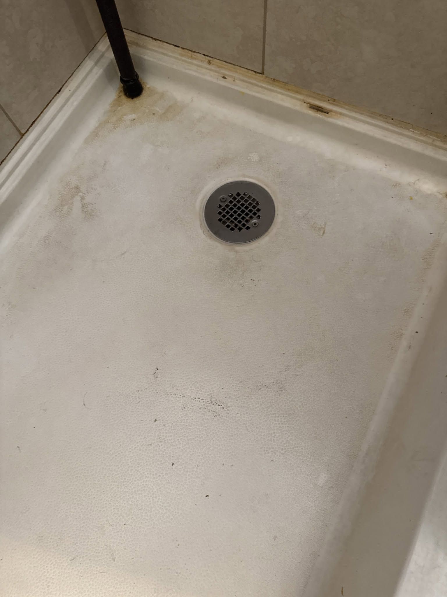 A white shower stall with a drain on the floor.