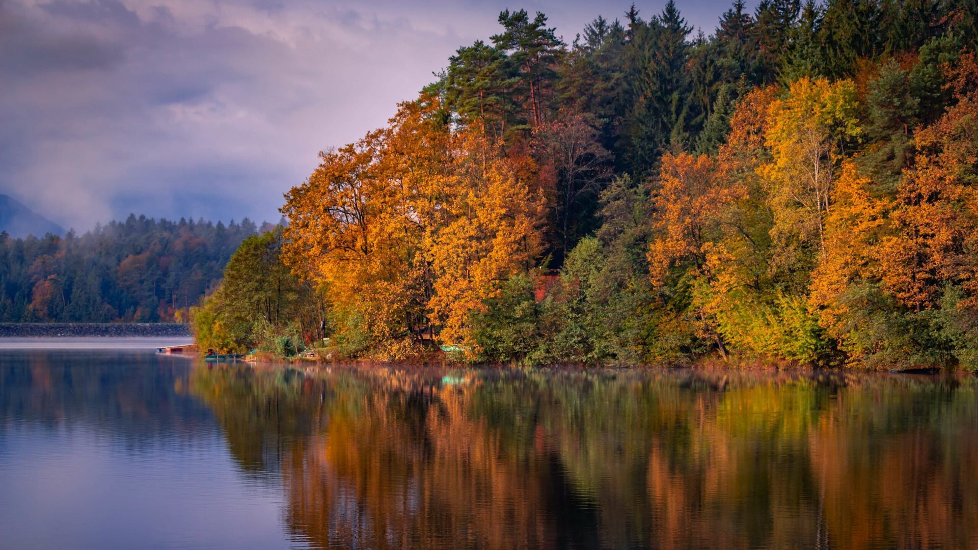 Autumn foliage reflected in calm lake water.
