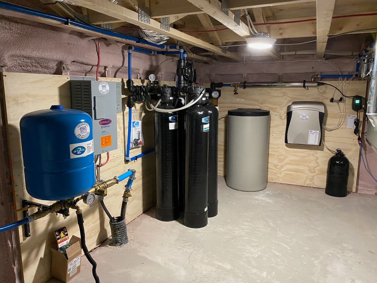 A basement with a lot of pipes and tanks.