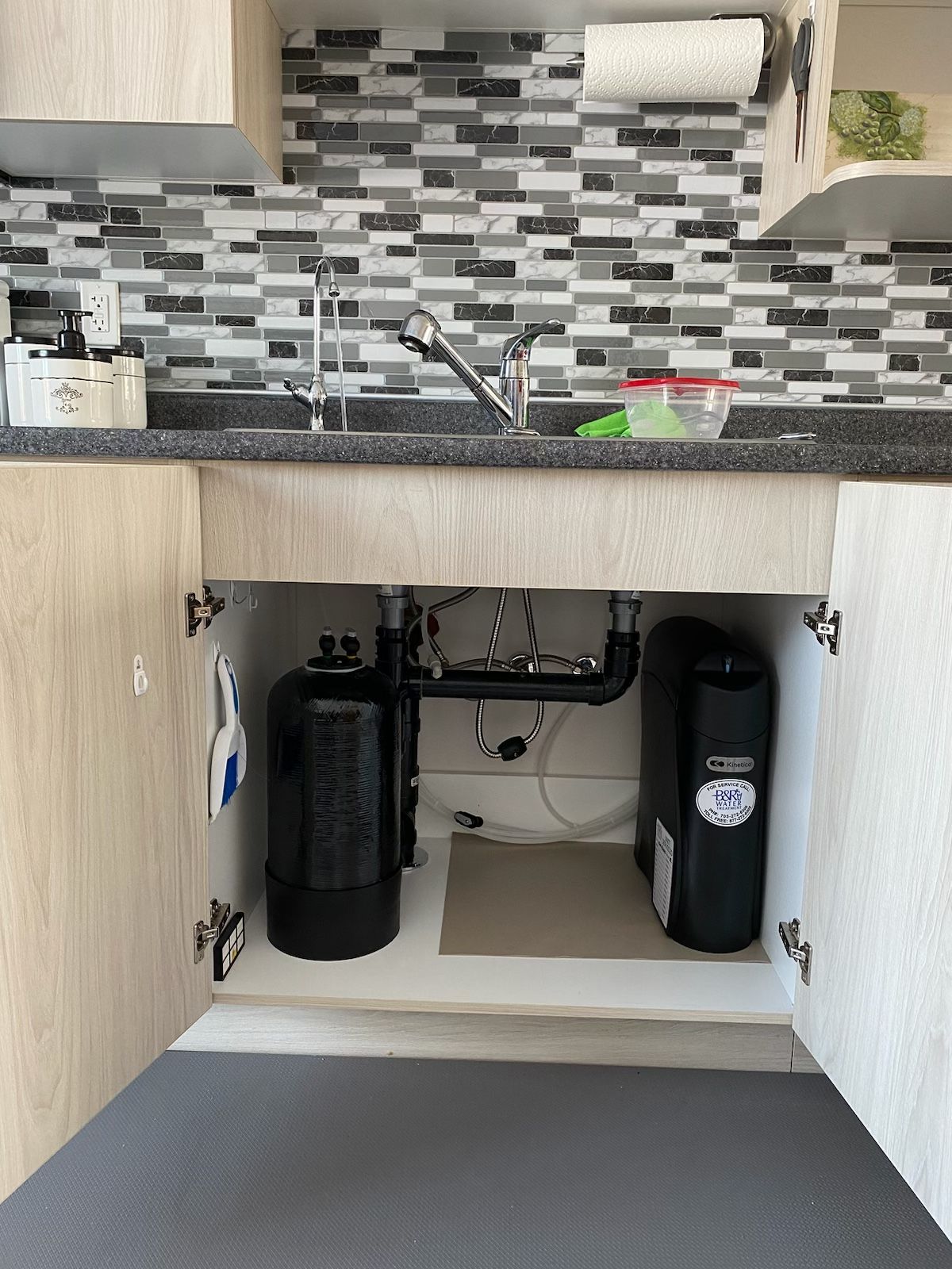 A kitchen with a sink , cabinets , and a paper towel hanging on the wall.
