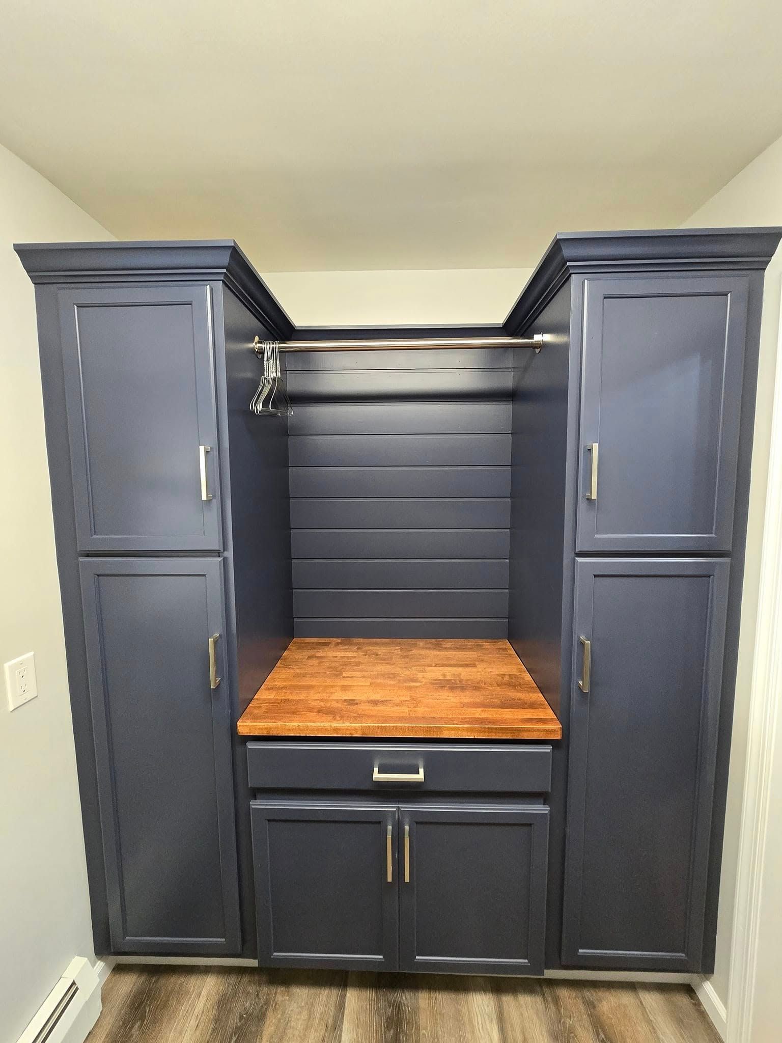 A laundry room with blue cabinets and a wooden counter top.