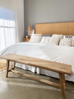 Un banco de madera está sentado frente a una cama en un dormitorio.