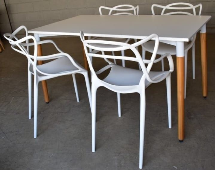 Una mesa blanca y sillas con patas de madera.