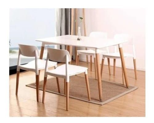 Una mesa de comedor y sillas están colocadas sobre una alfombra en una habitación.