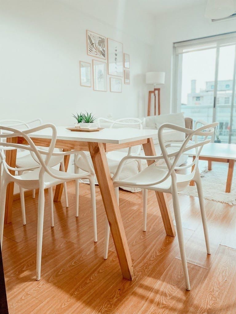 Un comedor con una mesa de madera y sillas blancas.