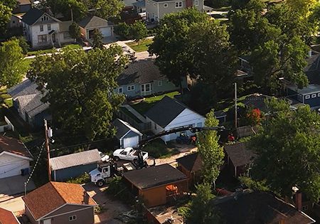 Aerial view of a residential neighborhood with houses, trees, and a utility truck in the street.