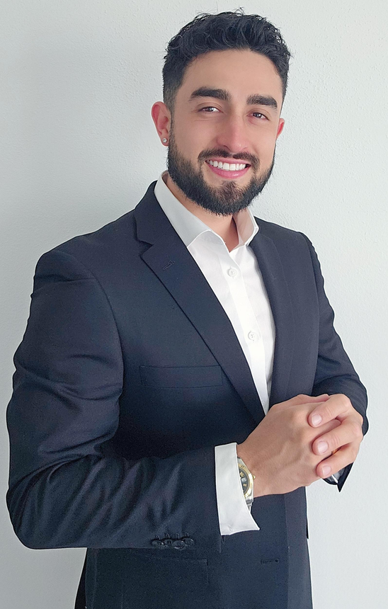 A woman is sitting at a desk with a laptop and a vase of flowers.