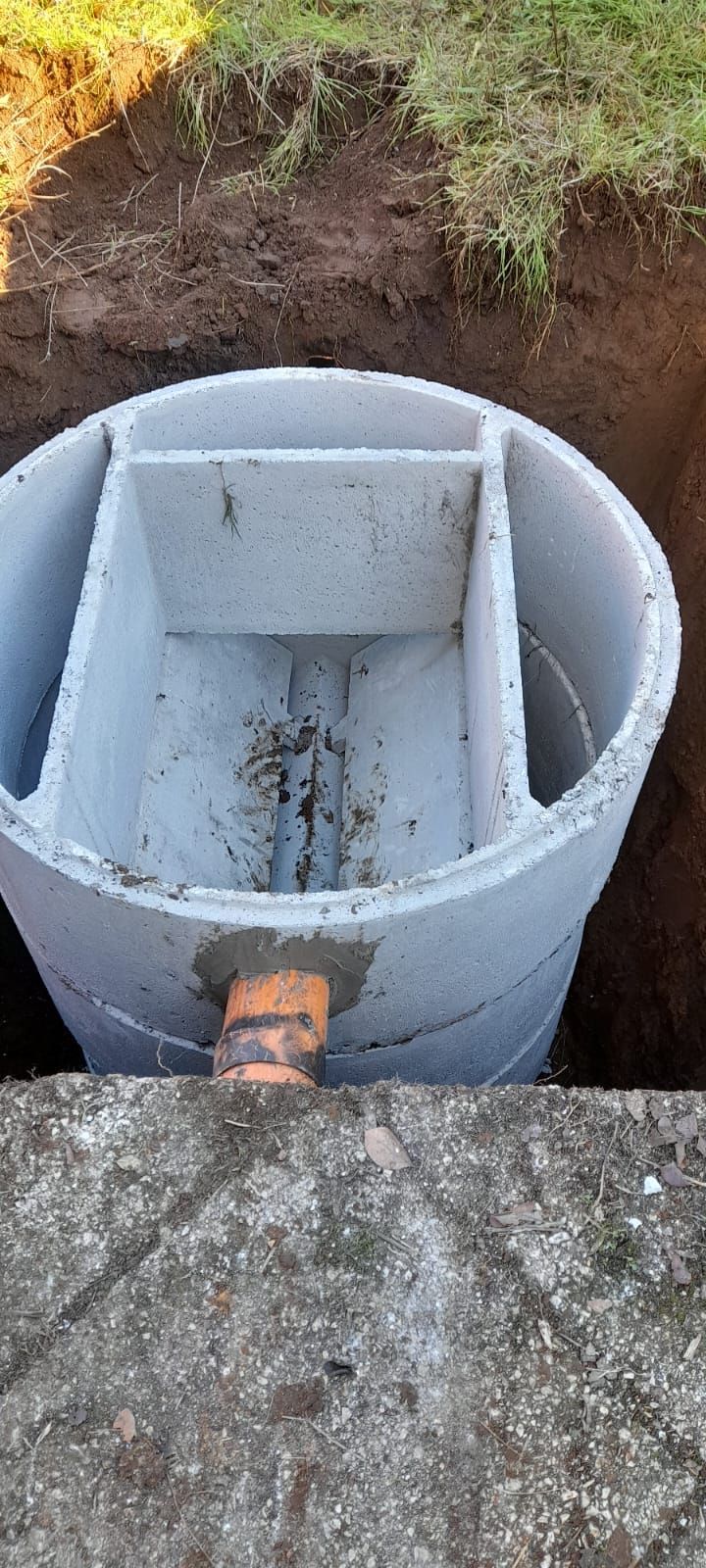 Camera di servizio circolare con divisorio in cemento e apertura per tubazione in una buca scavata