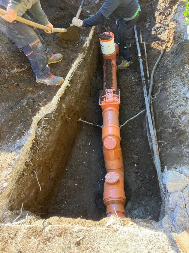 Escavatore e materiali da cantiere predisposti per lavori di scavo e posa tubazioni.