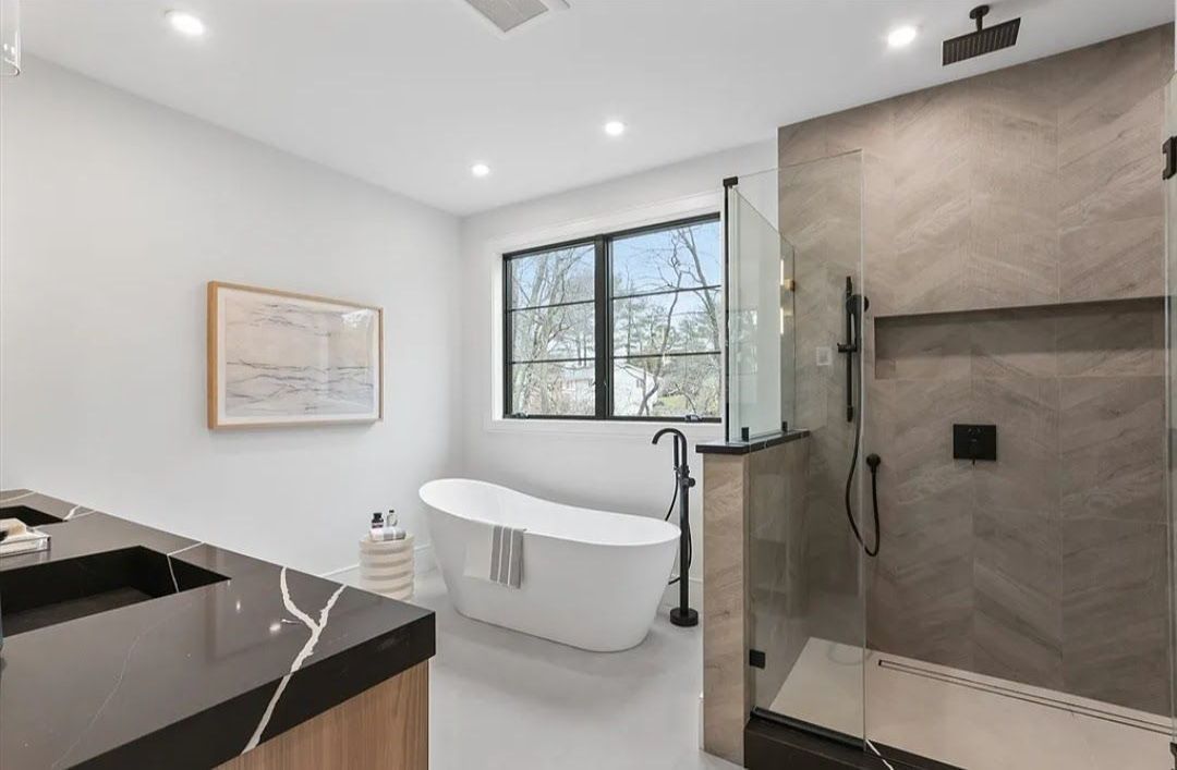 A bathroom with a tub , sink , shower and window.