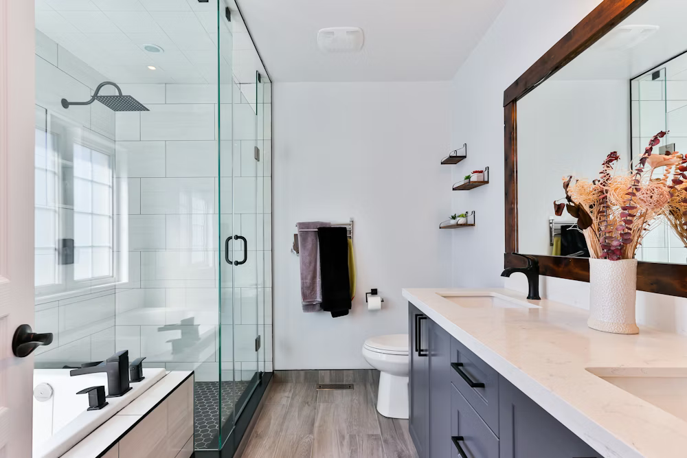 Bright modern bathroom with glass shower, vanity, mirror, and towel rack