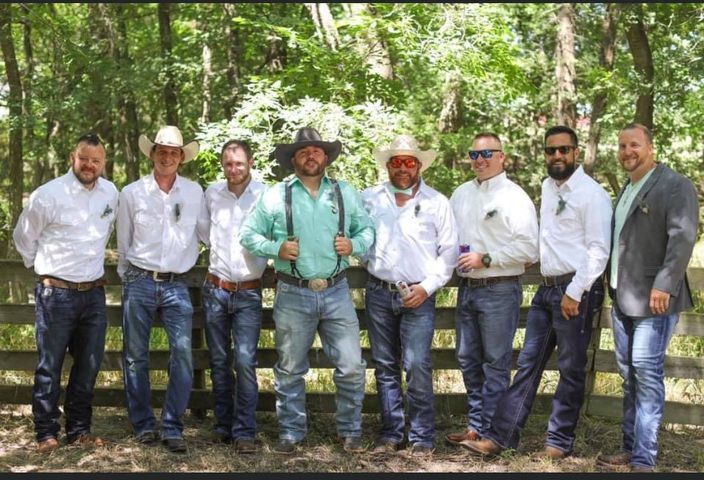 A group of men are posing for a picture in front of a fence.