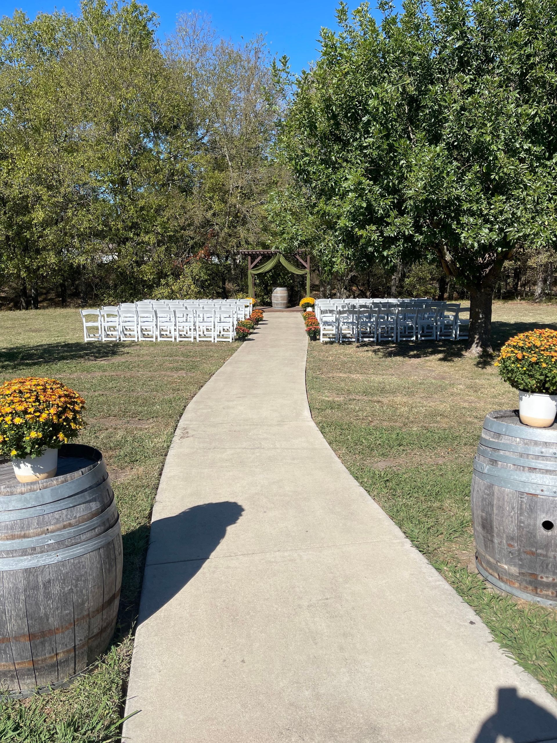 A concrete walkway lined with wooden benches leading to a wedding ceremony.