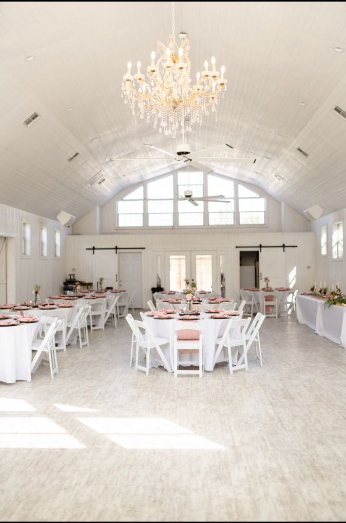 A large room with tables and chairs set up for a wedding reception.