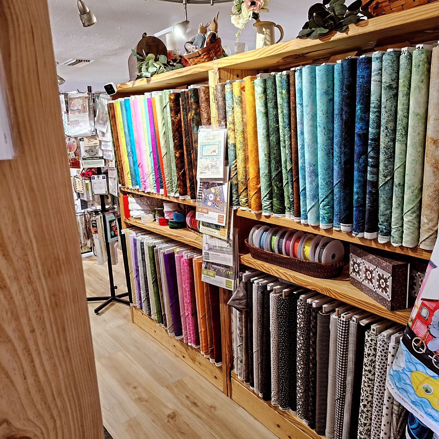 Fabric store aisle with shelves of colorful patterned fabric bolts