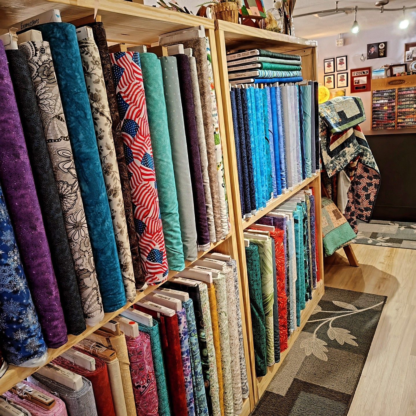 Fabric bolts displayed on wooden shelves in a colorful quilt shop interior