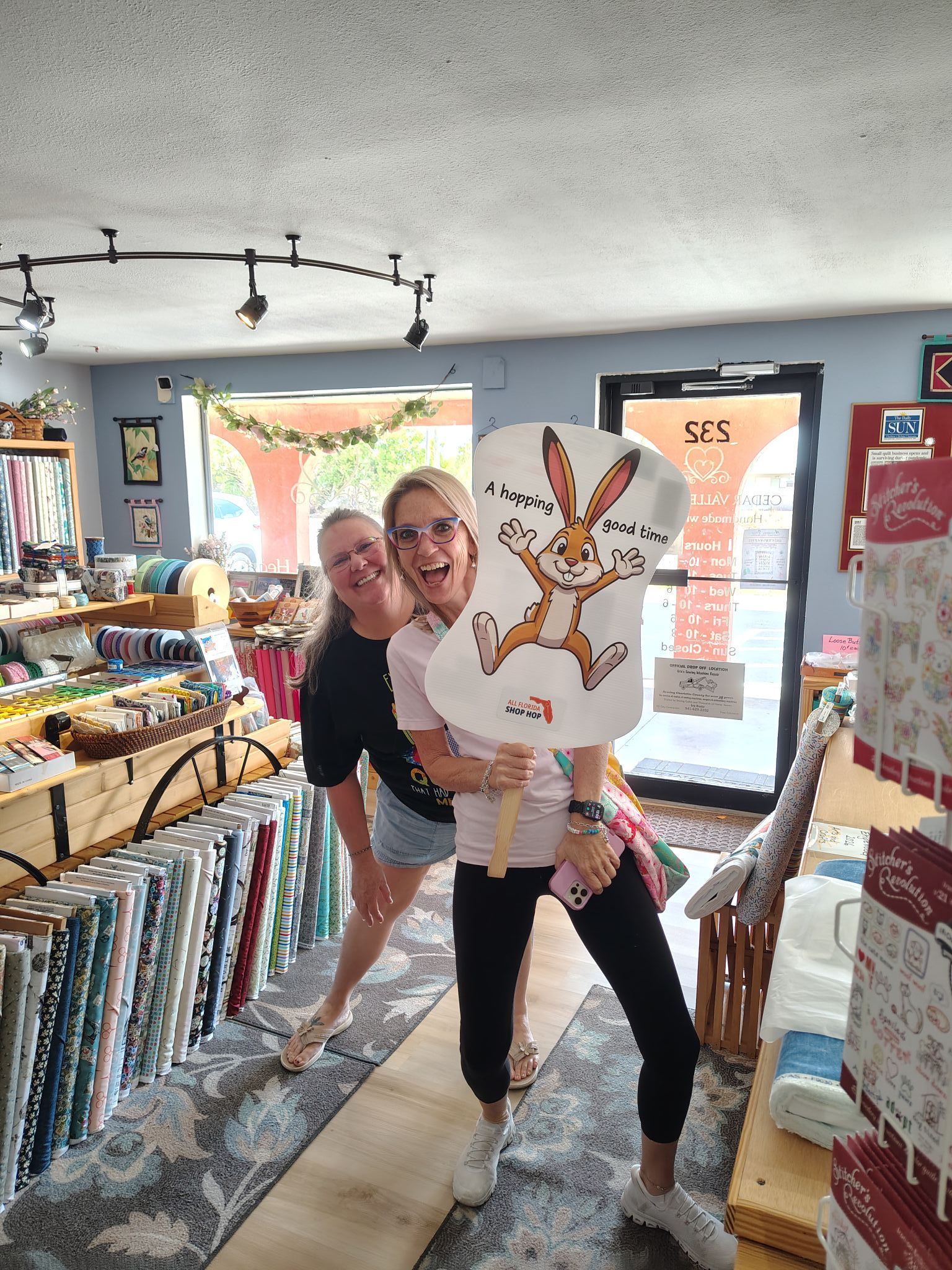 Two people holding a cartoon rabbit cutout in a colorful shop aisle