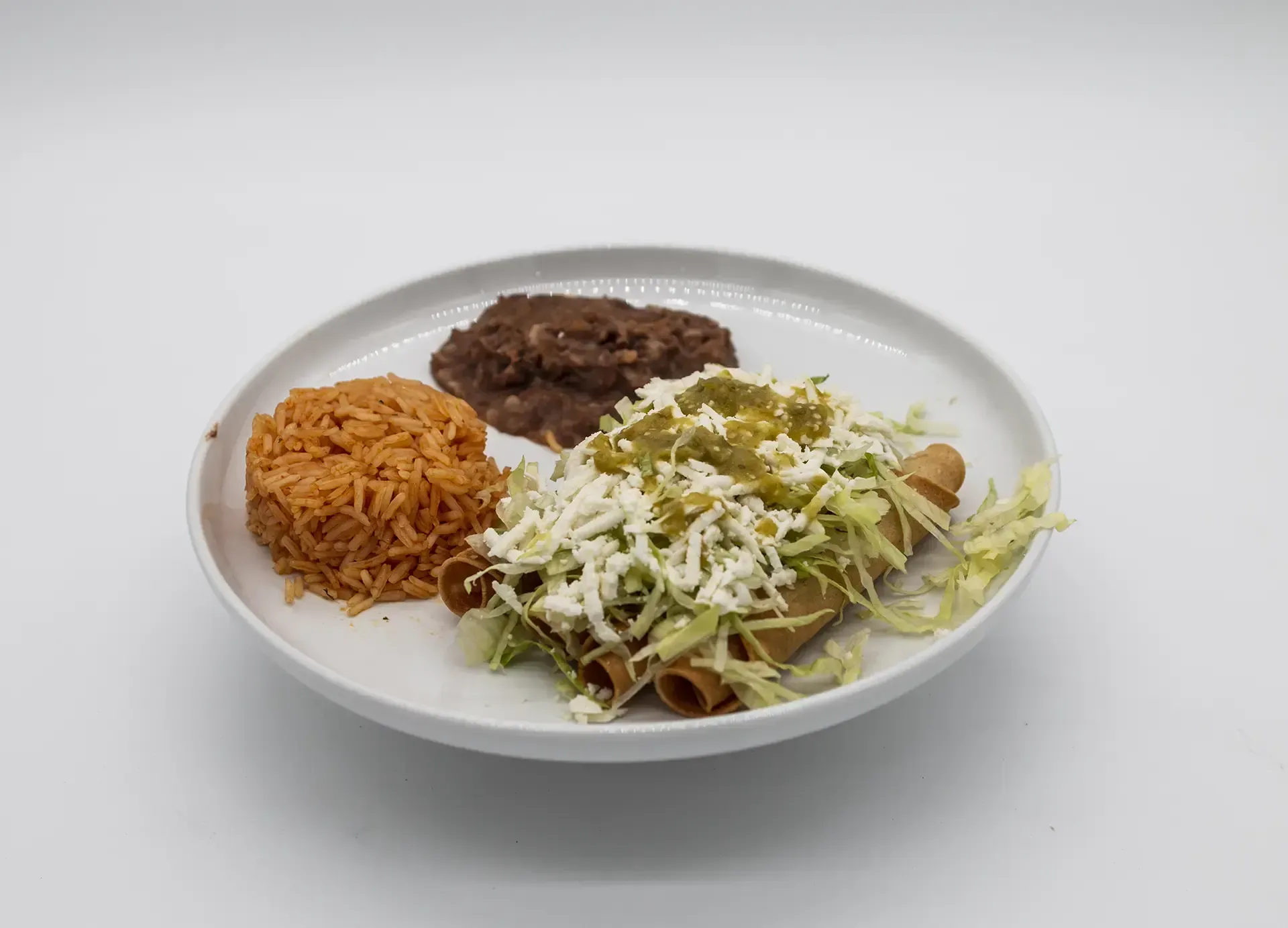 Plate with Mexican food: taquitos topped with cheese, salsa, lettuce, served with rice and beans.