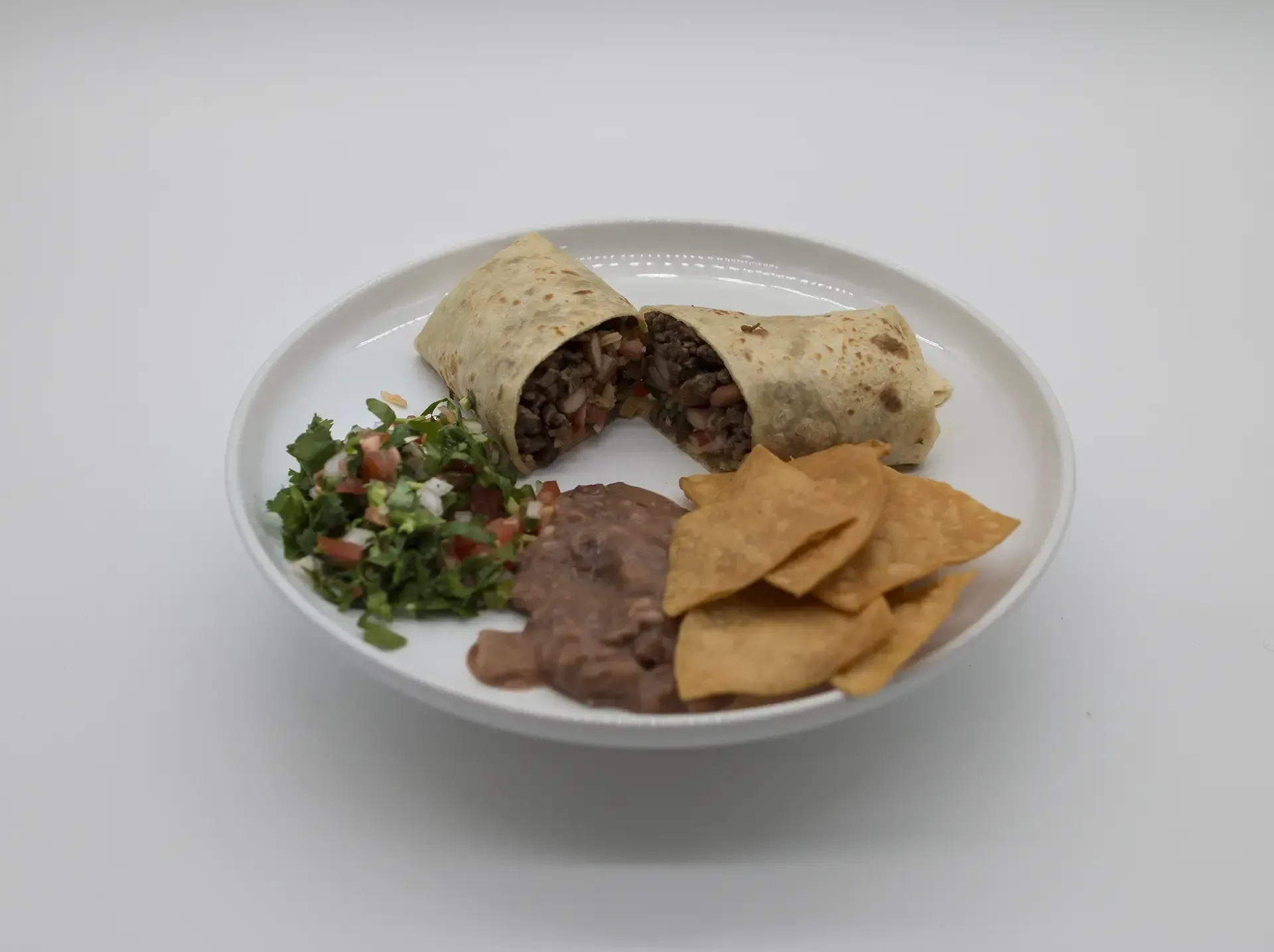 Plate of Mexican food: grilled steak, rice, refried beans with cheese, lime wedges.
