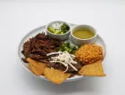 Plate of Mexican food: shredded meat, rice, beans, salsa, chips, lime, and onions.