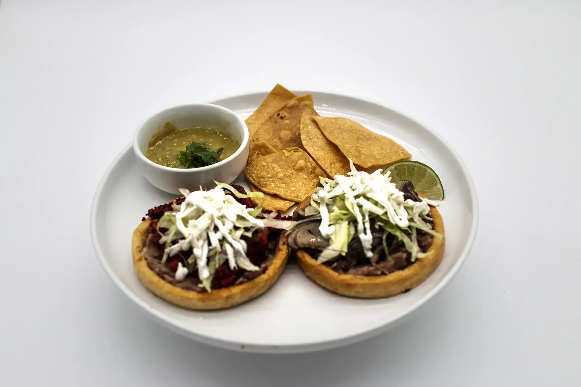 Plate of Mexican food: grilled steak, rice, refried beans with cheese, lime wedges.