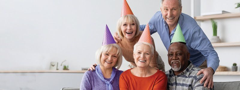 A group of elderly people wearing party hats are posing for a picture.