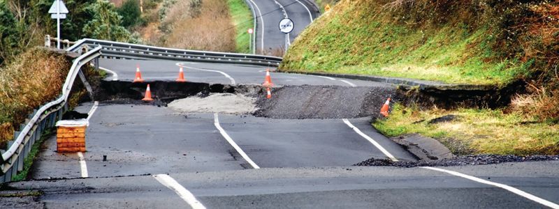 A road with a large sinkhole in the middle of it.