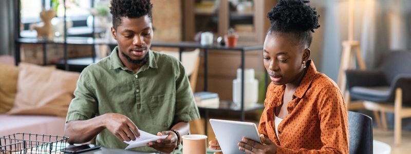 a couple looking at paperwork and a device together