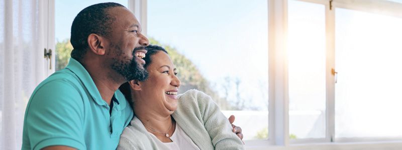 a man and a woman are sitting on a couch looking out a window .