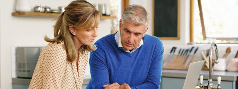 A couple looking at a computer and paper on a counter