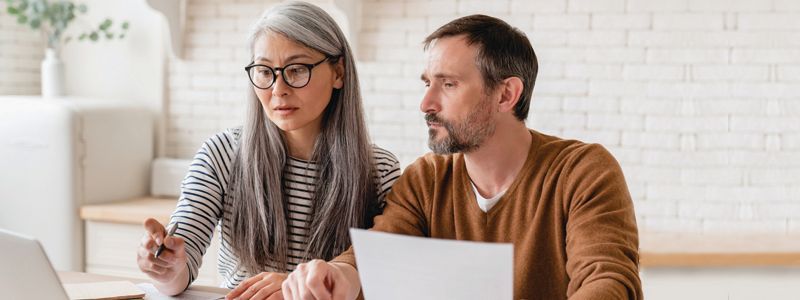 a-couple-looking-at-a-computer-screen-and-paper