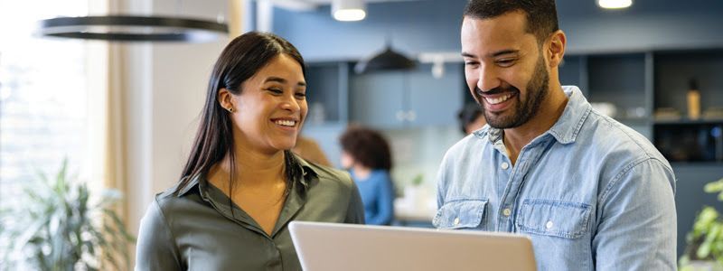 A man and a woman are looking at a laptop computer.