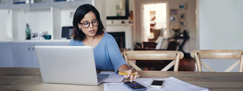 A woman is sitting at a table using a laptop computer.