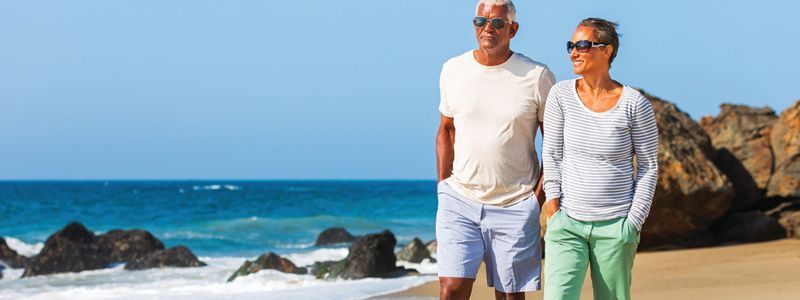 A man and a woman are walking on a beach.