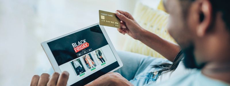 A woman is holding a credit card and a tablet while sitting next to a man.