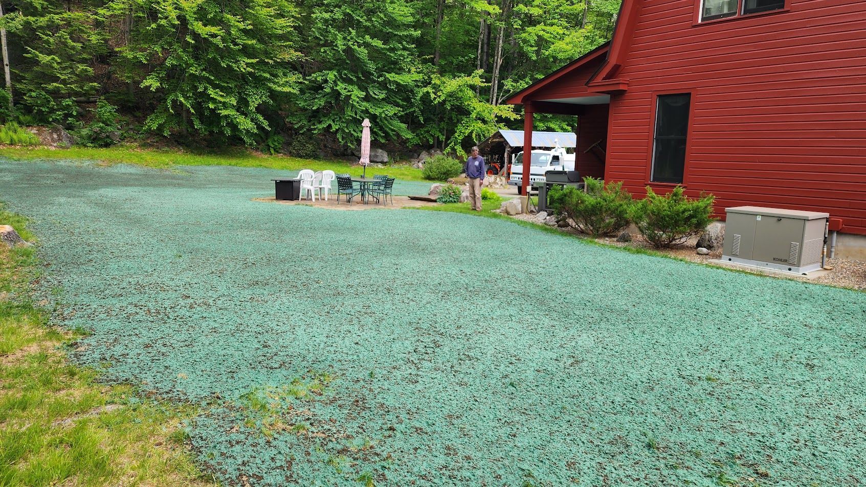 A red house with a green driveway in front of it.