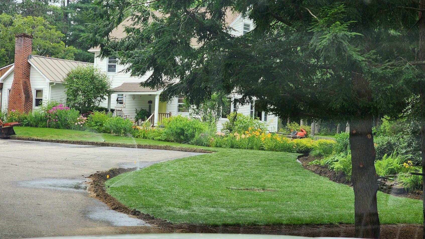 A driveway leading to a house with a chimney on the side of it.