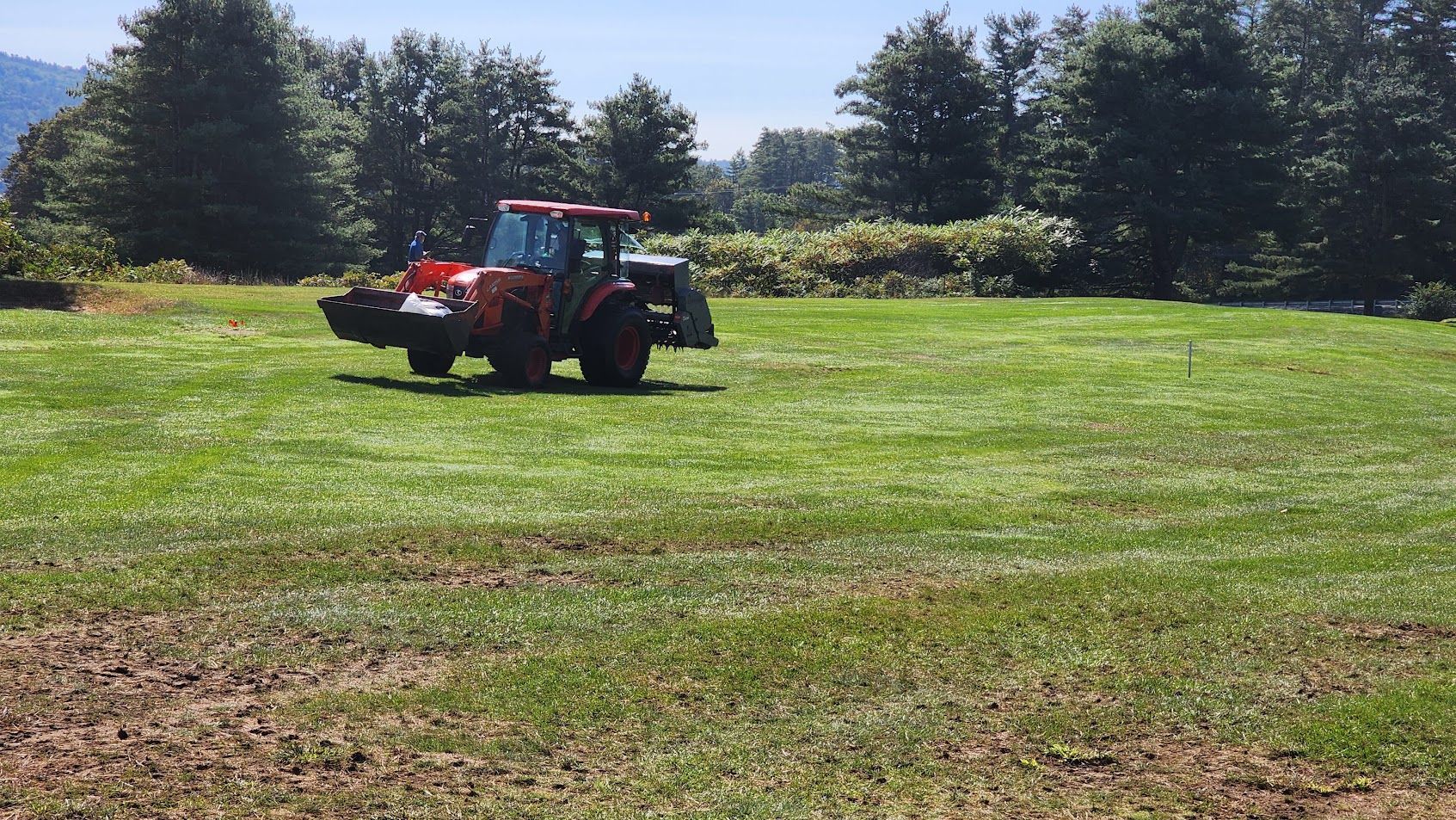 A red tractor is driving through a lush green field.