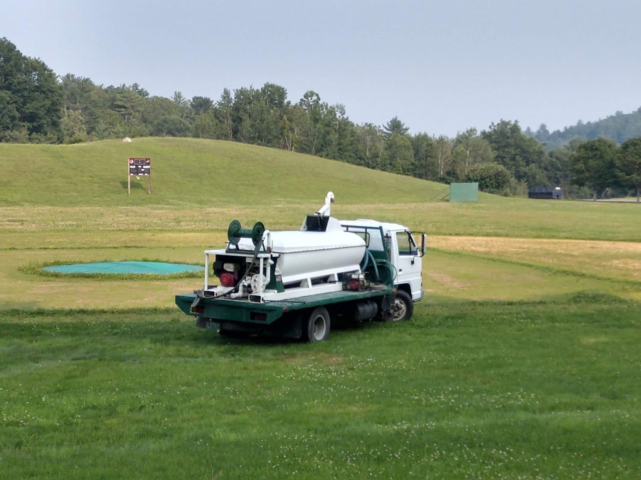 A white truck is parked in a grassy field.