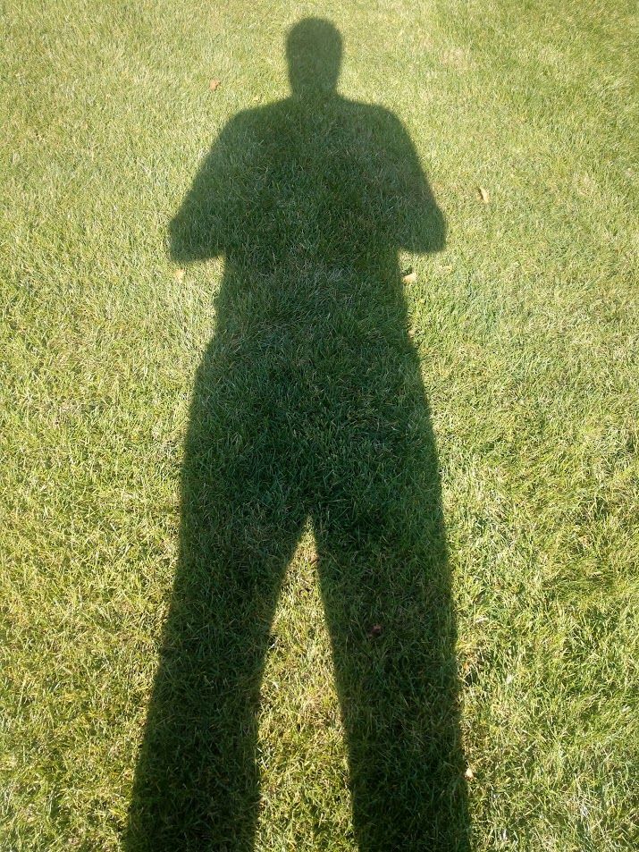 A shadow of a person standing in the grass.