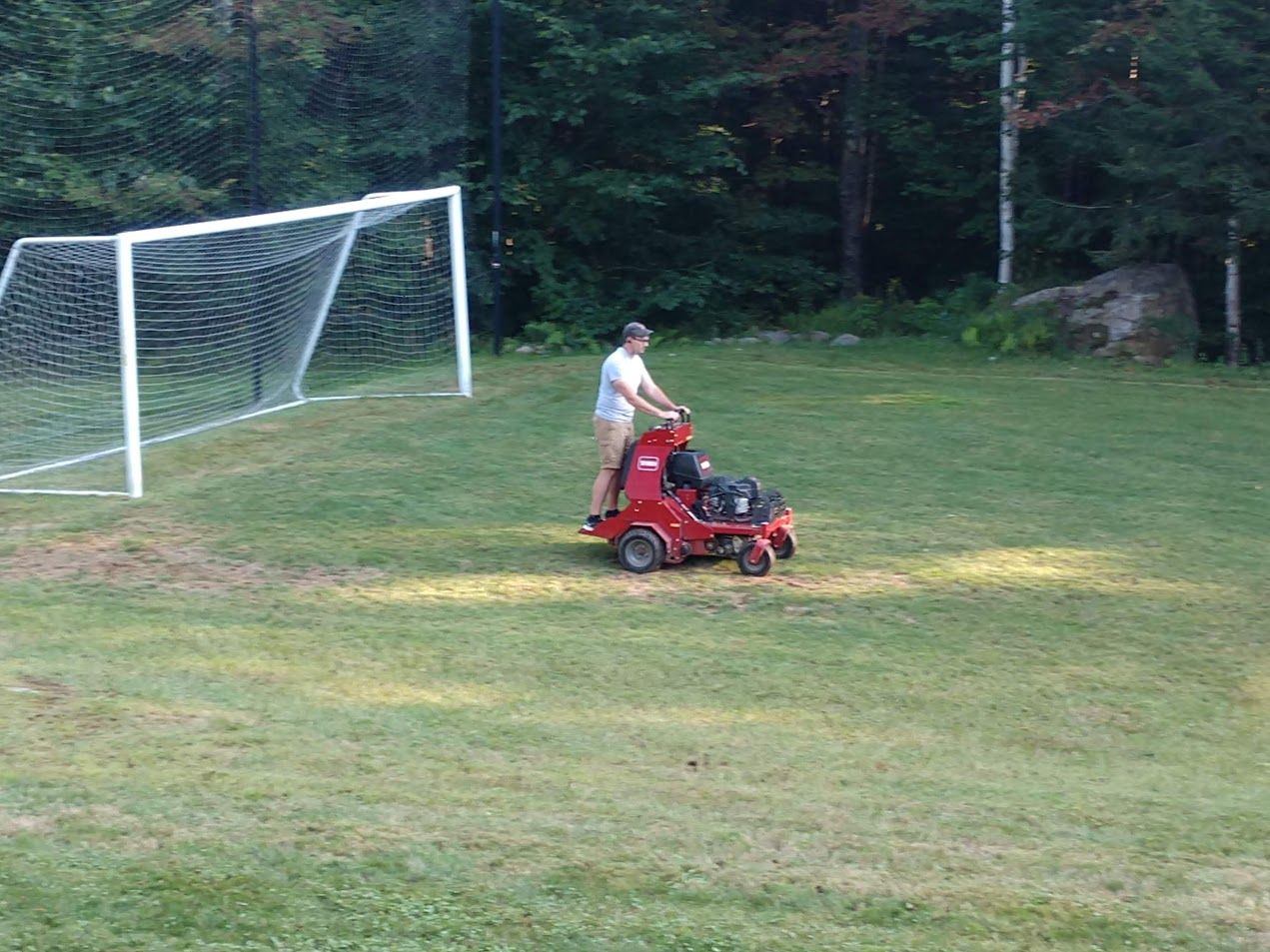 A man is riding a lawn mower on a soccer field.