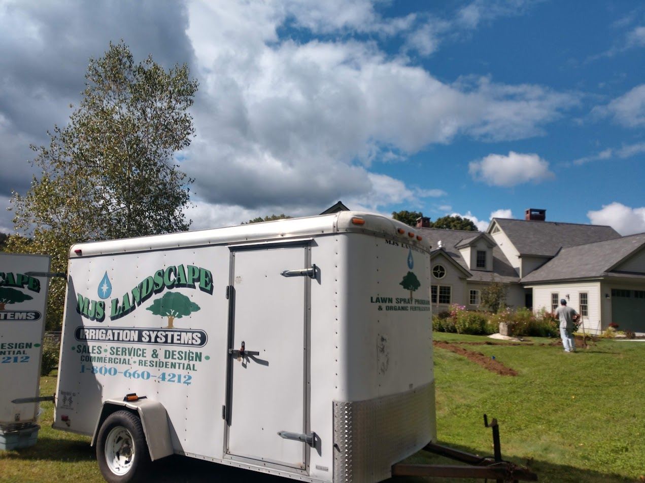 A lawn care trailer is parked in front of a house